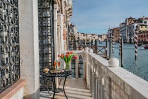 einen Tisch mit Blumen auf einem Balkon neben dem Wasser in der Unterkunft La Loggia Grand Canal in Venedig