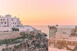 a building on a cliff with the ocean in the background at POSEA - Polignano Sea Suites in Polignano a Mare