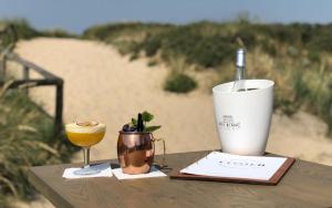 una mesa con una copa y una taza en la playa en Sea en Egmond aan Zee