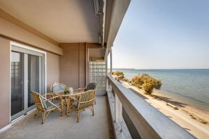 balcón con mesa, sillas y vistas al océano en Metaxa Seafront Apartment, en Perea
