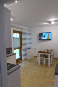 a kitchen and dining room with a table and a tv at APARTAMENT PRZY PLAŻY in Rowy