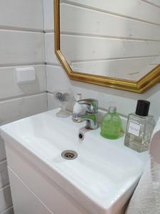 a bathroom sink with a mirror and a soap dispenser on it at Saunaboat Haikara in Jorvas