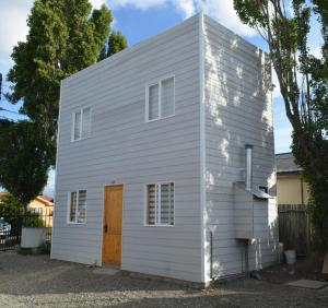 une petite maison blanche avec une porte marron dans l'établissement Sima Michi, à Puerto Natales