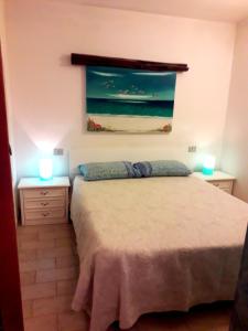 a bedroom with a bed and two lights on two tables at Sardinia Yellow House in Solanas