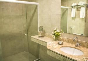 uma casa de banho com um lavatório e um chuveiro em Farol de Itapuã Praia Hotel em Salvador
