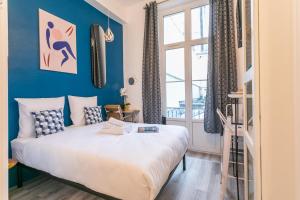 a bedroom with a bed with blue walls and a window at Apartments WS Marais - République in Paris