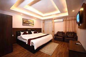 een slaapkamer met een bed, een tv en een bank bij Greatwall International Hotel in Kathmandu