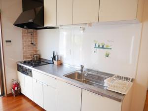 a kitchen with white cabinets and a sink at 子供部屋のある一棟貸切り 奄宿り Amayadori in Amami