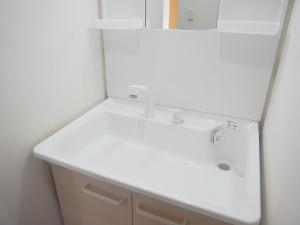 La salle de bains est pourvue d'un lavabo blanc. dans l'établissement 子供部屋のある一棟貸切り 奄宿り Amayadori, à Amami