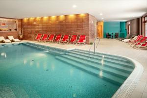 a large swimming pool with red chairs in a building at Grund Resort Golf and Ski in Mladé Buky