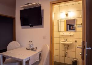 Hotel Bouzid - Laatzen في هانوفر: غرفة مع طاولة ومغسلة وتلفزيون