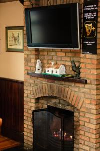 a brick fireplace with a tv on top of it at The Yeats County Inn Hotel in Tobercurry