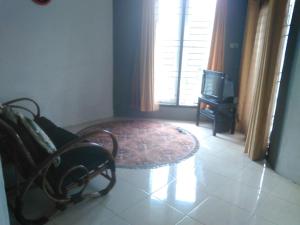 sala de estar con silla, mesa y TV en Villa Sahala Simanjuntak en Balige