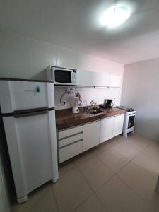 een keuken met een witte koelkast en een wastafel bij Rosa Branca Facilities Apartamentos in Maceió
