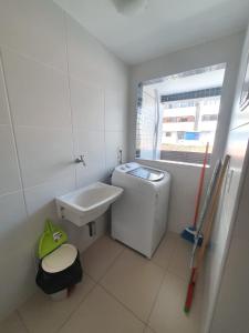 uma casa de banho com um lavatório e uma máquina de lavar roupa em Rosa Branca Facilities Apartamentos em Maceió