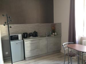 a kitchen with a sink and a microwave and a table at STUDIO proche gare avec kitchenette et wifi - porte rouge in Thiviers