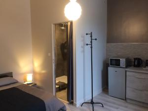 a bedroom with a bed and a light on a pole at STUDIO proche gare avec kitchenette et wifi - porte rouge in Thiviers