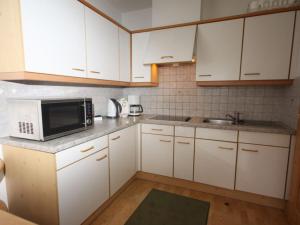 uma cozinha com armários brancos e um micro-ondas em Panoramawohnung Bad Hofgastein em Bad Hofgastein