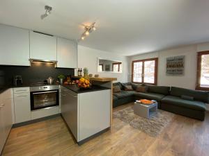 a kitchen and a living room with a couch at Casa al Lag - direkt am Laaxersee in Laax