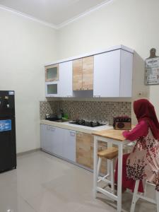 a woman sitting at a table in a kitchen at Villa B9us Batu in Karangploso