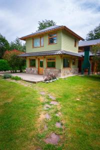 a yellow house with a lawn in front of it at Paillahuen in Villa La Angostura