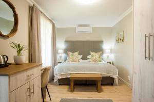 Schlafzimmer mit einem Bett mit einem Tisch und einem Spiegel in der Unterkunft Four Palms Accommodation in Durbanville