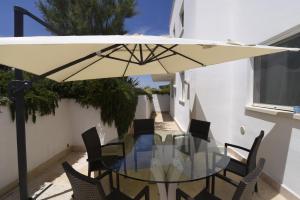 een glazen tafel met stoelen en een parasol op een balkon bij Villa Emiele in Mola di Bari