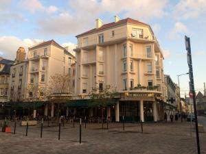 two tall buildings on a street in a city at LE NID DES HALLES, au cœur du Boulingrin in Reims