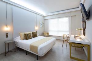 Schlafzimmer mit einem Bett, einem Schreibtisch und einem Fenster in der Unterkunft Hotel Ciudad de Vigo in Vigo