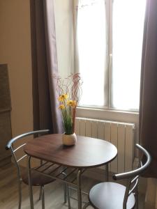 a table with a vase of flowers on it at STUDIO proche gare avec kitchenette et wifi - porte rouge in Thiviers