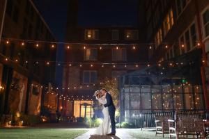 una sposa e uno sposo che si baciano davanti a un edificio di Hotel Covington Cincinnati Riverfront a Covington