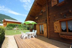 une terrasse en bois avec une table et un parasol vert dans l'établissement Chalet chaleureux - 9 personnes - 3km des pistes - proche Morzine - Iaorana, à Saint-Jean-dʼAulps
