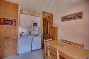 cocina con mesa de madera y nevera blanca en APPARTEMENT PROCHE MORZINE CENTRE ET REMONTEES MECANIQUES - Orée de Morzine 24A, en Montriond