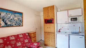 Una sala de estar con un sofá y una cocina. en APPARTEMENT PROCHE MORZINE CENTRE ET REMONTEES MECANIQUES - Orée de Morzine 24A, en Montriond