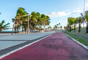 uma estrada com palmeiras ao lado de uma praia em Farol de Itapuã Praia Hotel em Salvador