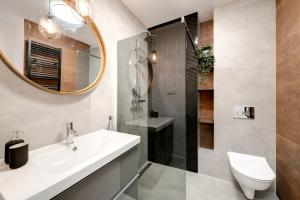 a bathroom with a sink and a shower and a mirror at Dom & House - Apartments Winter Residence in Gdańsk