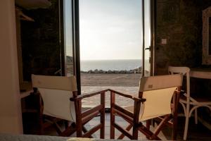 two chairs sitting on a porch looking out at the ocean at Casa Borealis in Naxos Chora