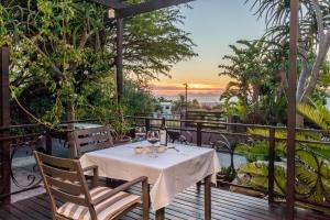 a table and chairs on a deck with the sunset at SW1 Lodge in Somerset West