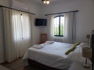 1 dormitorio con 1 cama blanca grande y cortinas blancas en Portal de la Montaña en Villa Carlos Paz