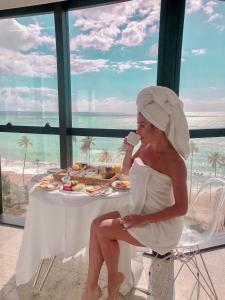 a woman sitting at a table with a plate of food at Hotel Brisa Tower Maceió in Maceió