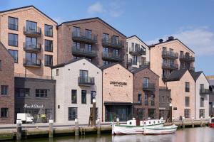 a group of buildings next to a river with boats at Lighthouse Hotel & Spa in Büsum