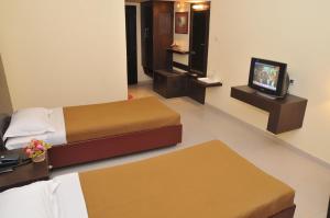 Hotel Vijayentra في بونديتْشيري: غرفة فندقية بسريرين وتلفزيون