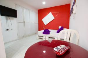 Habitación con mesa y pared roja. en QuillaHost Guesthouse, en Barranquilla