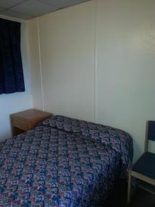 Americana Motel في Avenel: غرفة نوم بسرير وكرسي