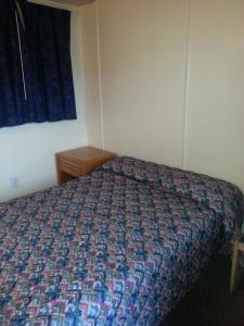 a bedroom with a bed with a colorful bedspread at Americana Motel in Avenel