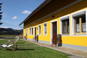 um edifício amarelo com bancos à frente em Ferienwohnung Moitz em Heimschuh