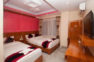 a bedroom with two beds and a flat screen tv at Kathmandu Regency Hotel in Kathmandu