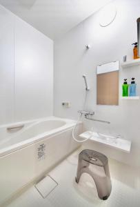 ein weißes Bad mit einem WC und einer Badewanne in der Unterkunft Tsurui Nijo 鶴居二条 in Kyoto