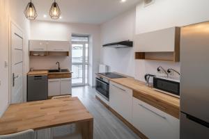 a kitchen with white cabinets and a wooden counter top at Around the World Vision Apartment - Centrum in Opole