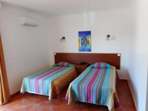una camera con due letti con lenzuola colorate di Agua Marinha ROSA- Hotel ad Albufeira